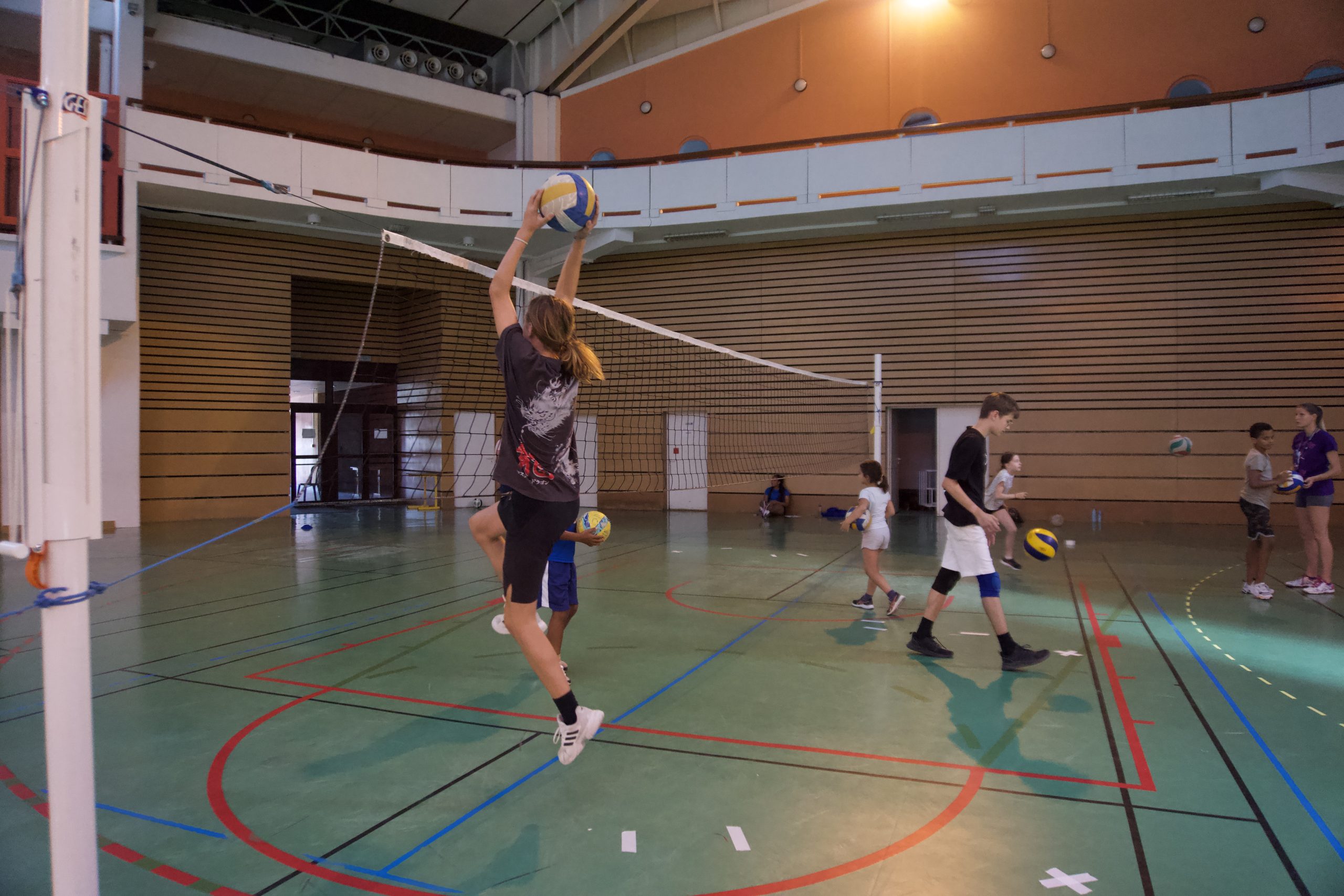 Enfants jouant au volley en salle.