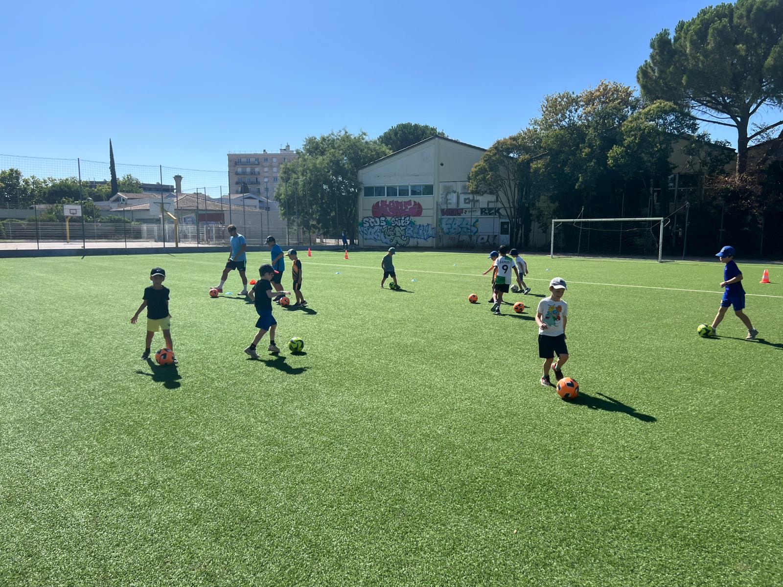 Enfants jouant au football sur un terrain extérieur.