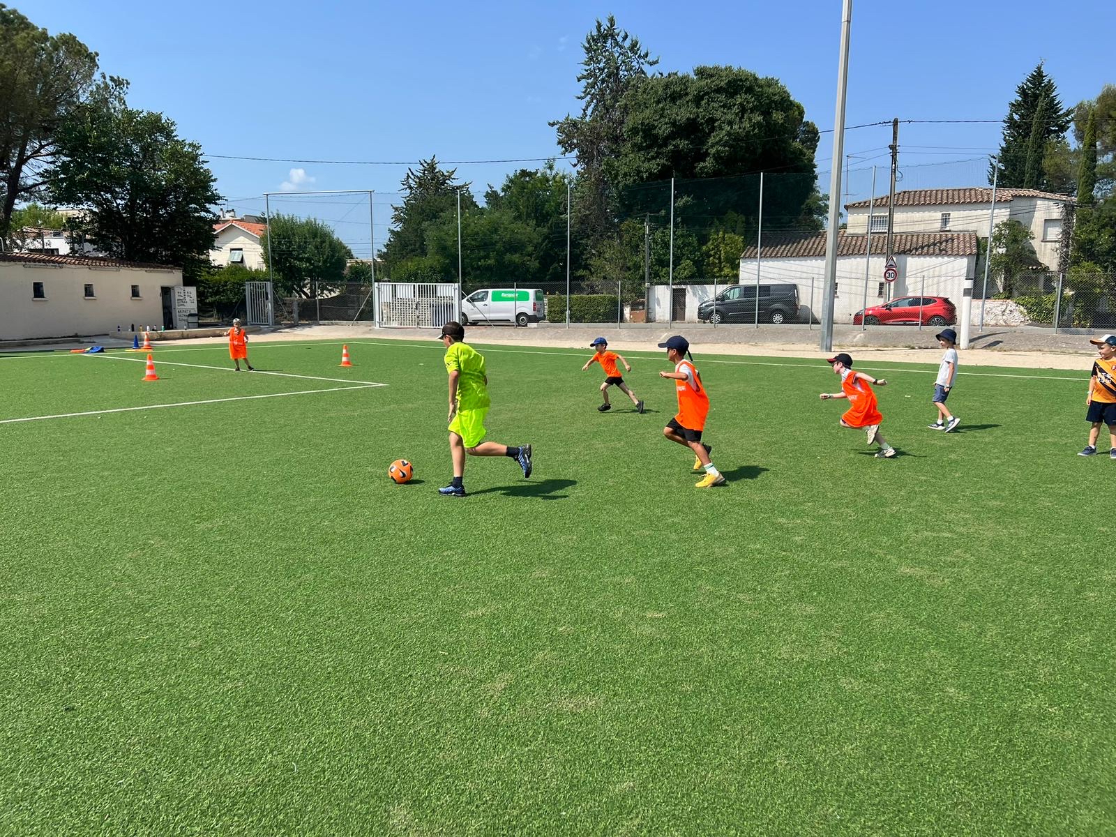 Enfants jouant au football sur un terrain herbeux.