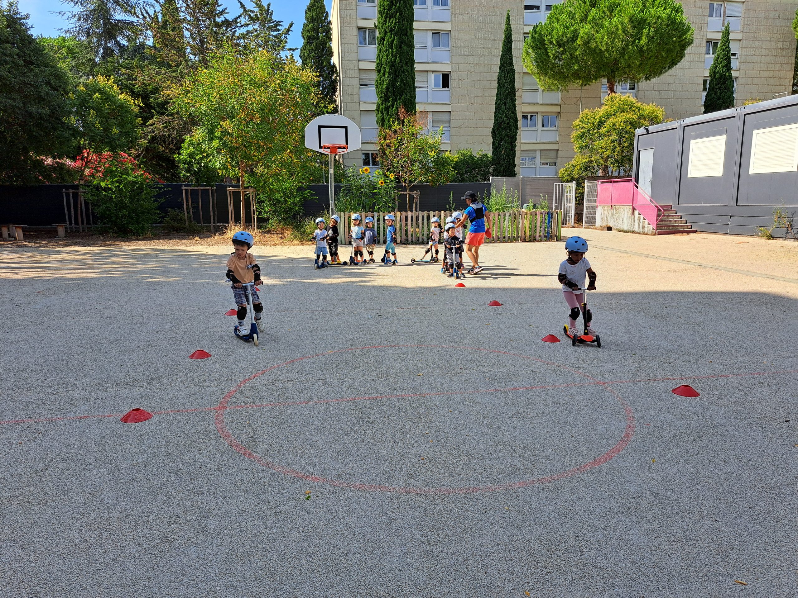 Enfants en trottinette sur terrain de jeu.
