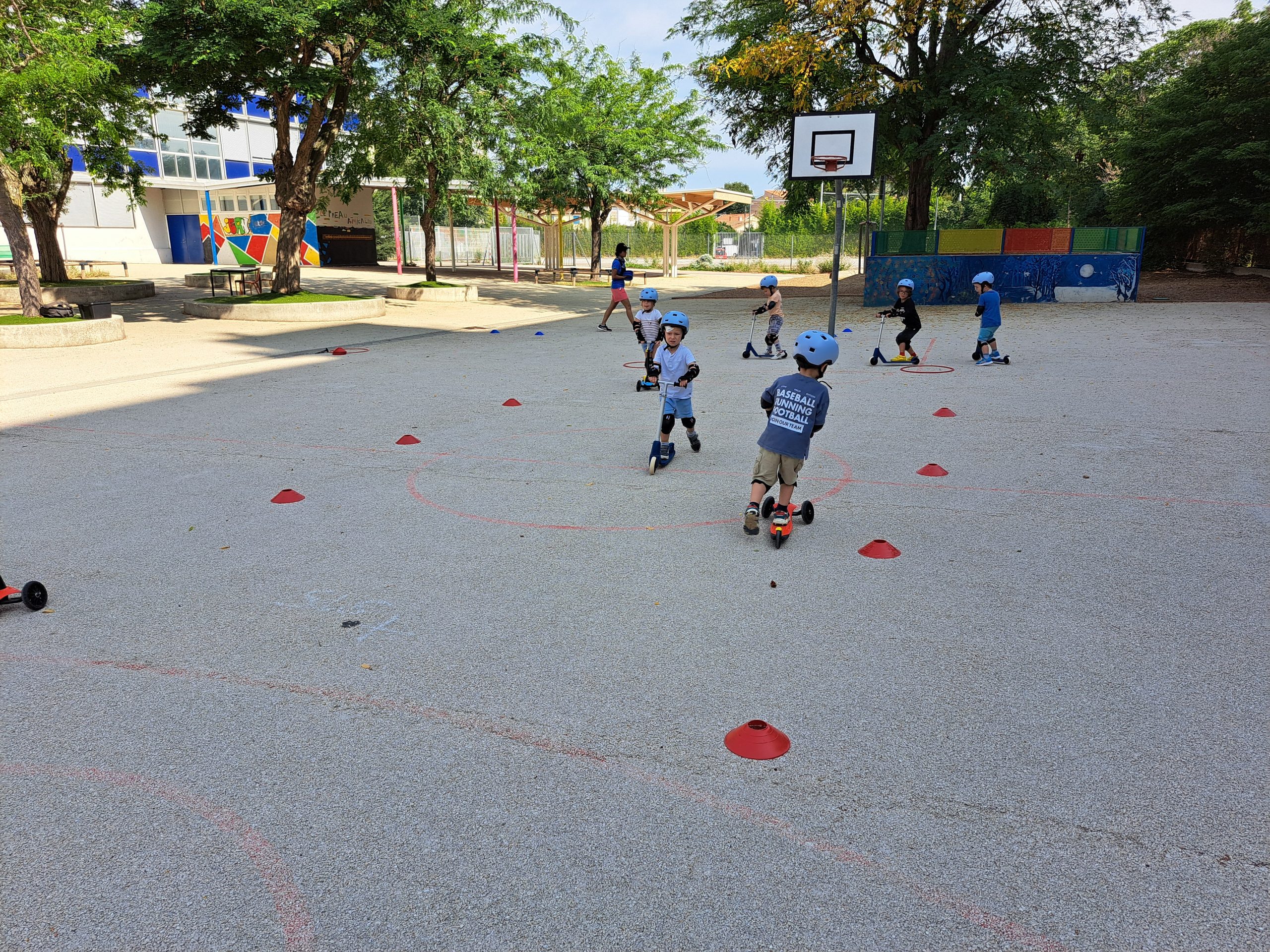 Enfants faisant de la trottinette dans une cour d'école.