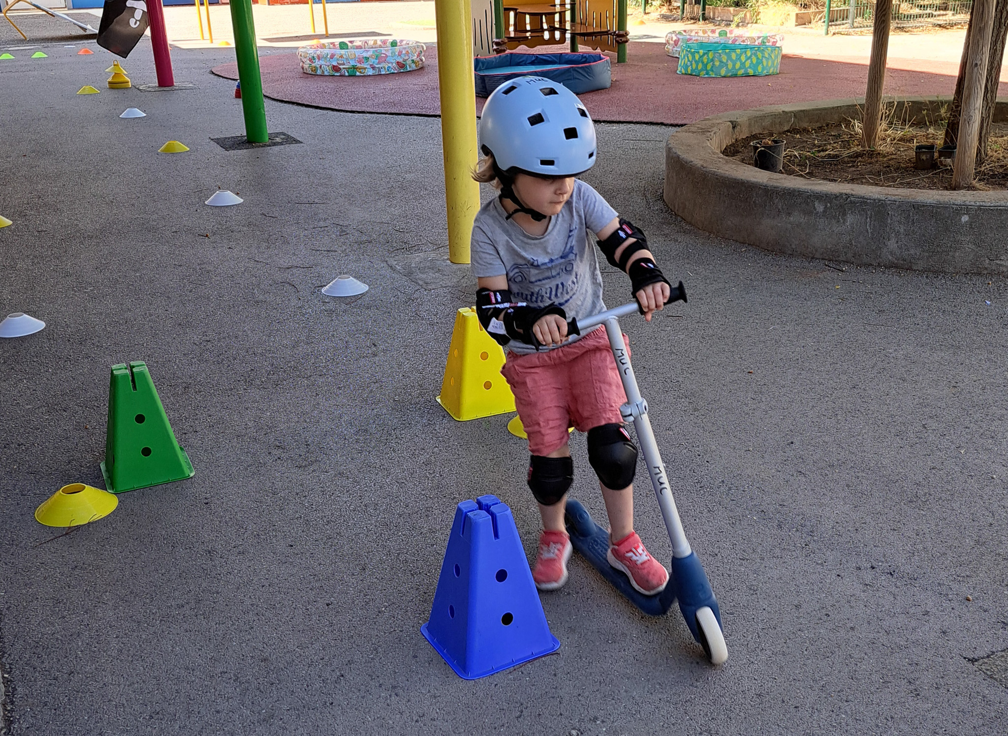 Enfant en trottinette avec casque sur parcours.