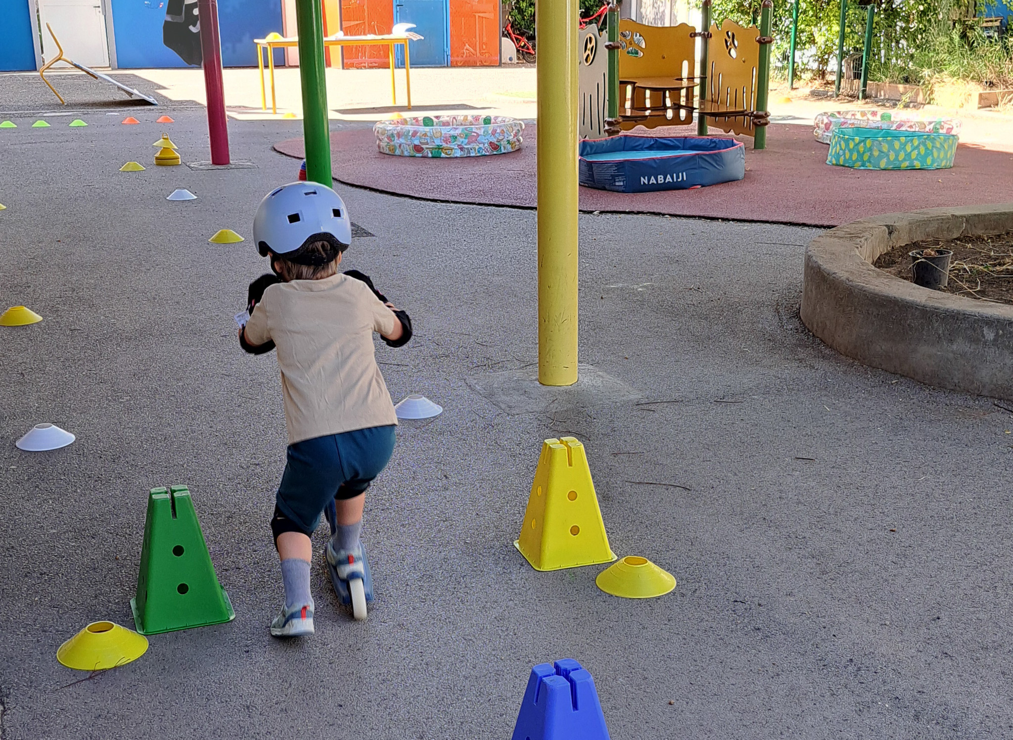 Enfant en trottinette dans une cour de récréation.