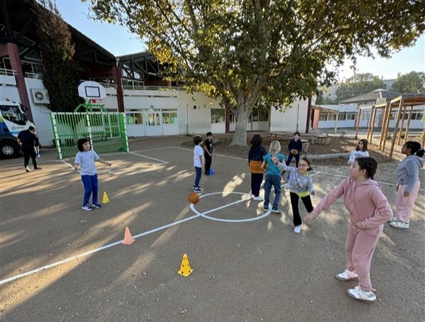 Enfants jouant au basketball dans une cour d'école.