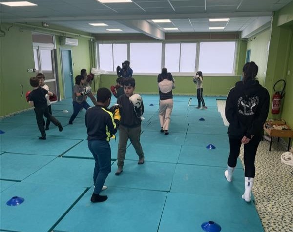 Enfants pratiquant la boxe dans une salle verte.
