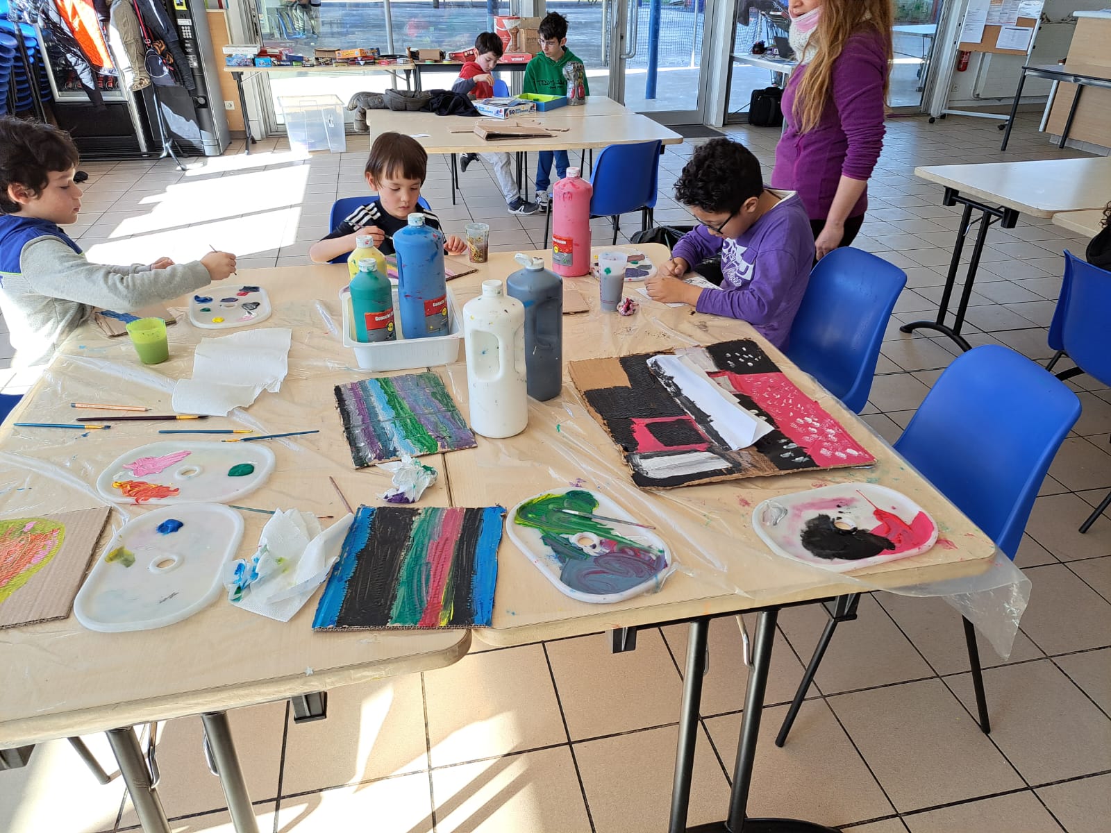 Enfants peignent sur une table avec des couleurs vives.