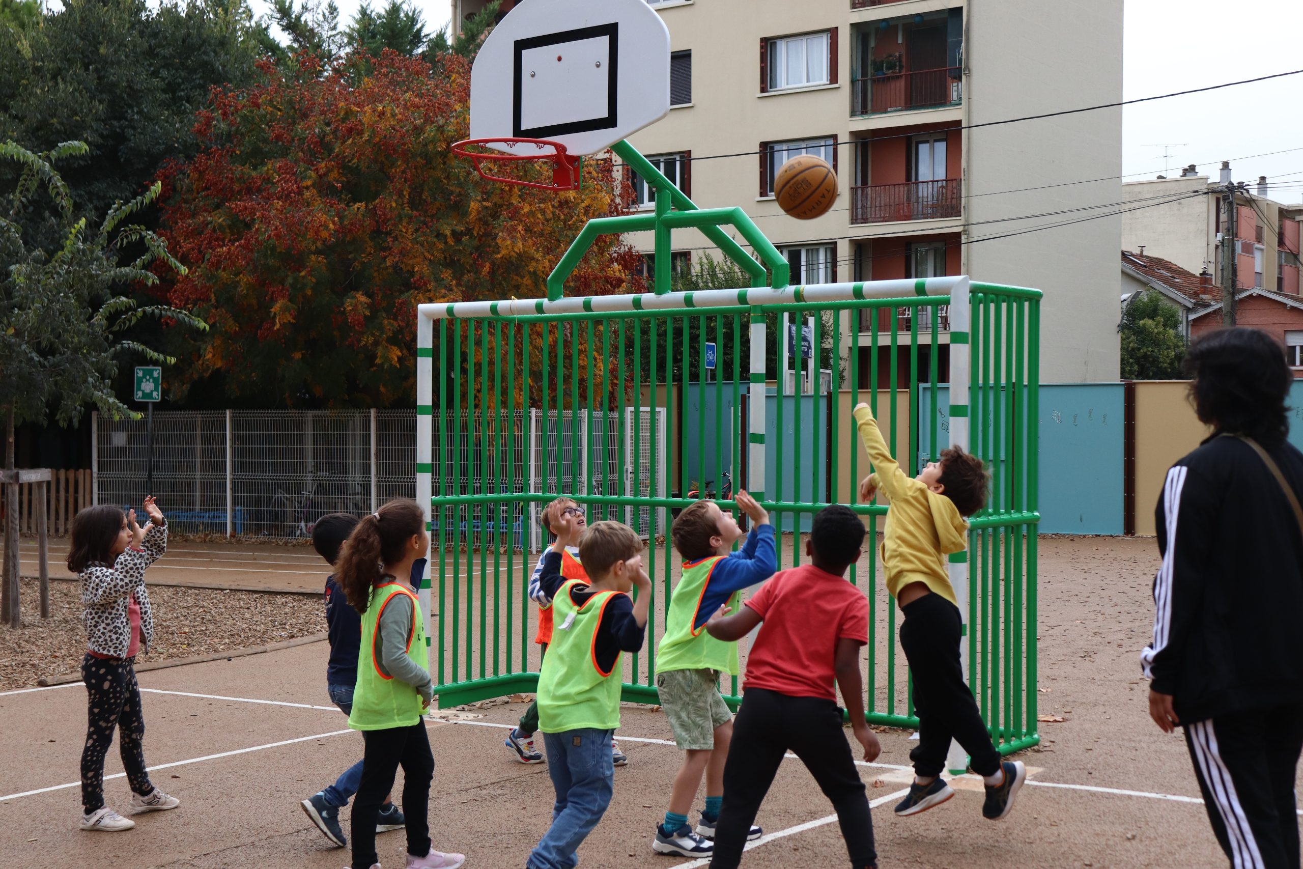 Enfants jouant au basket dans une cour d'école.