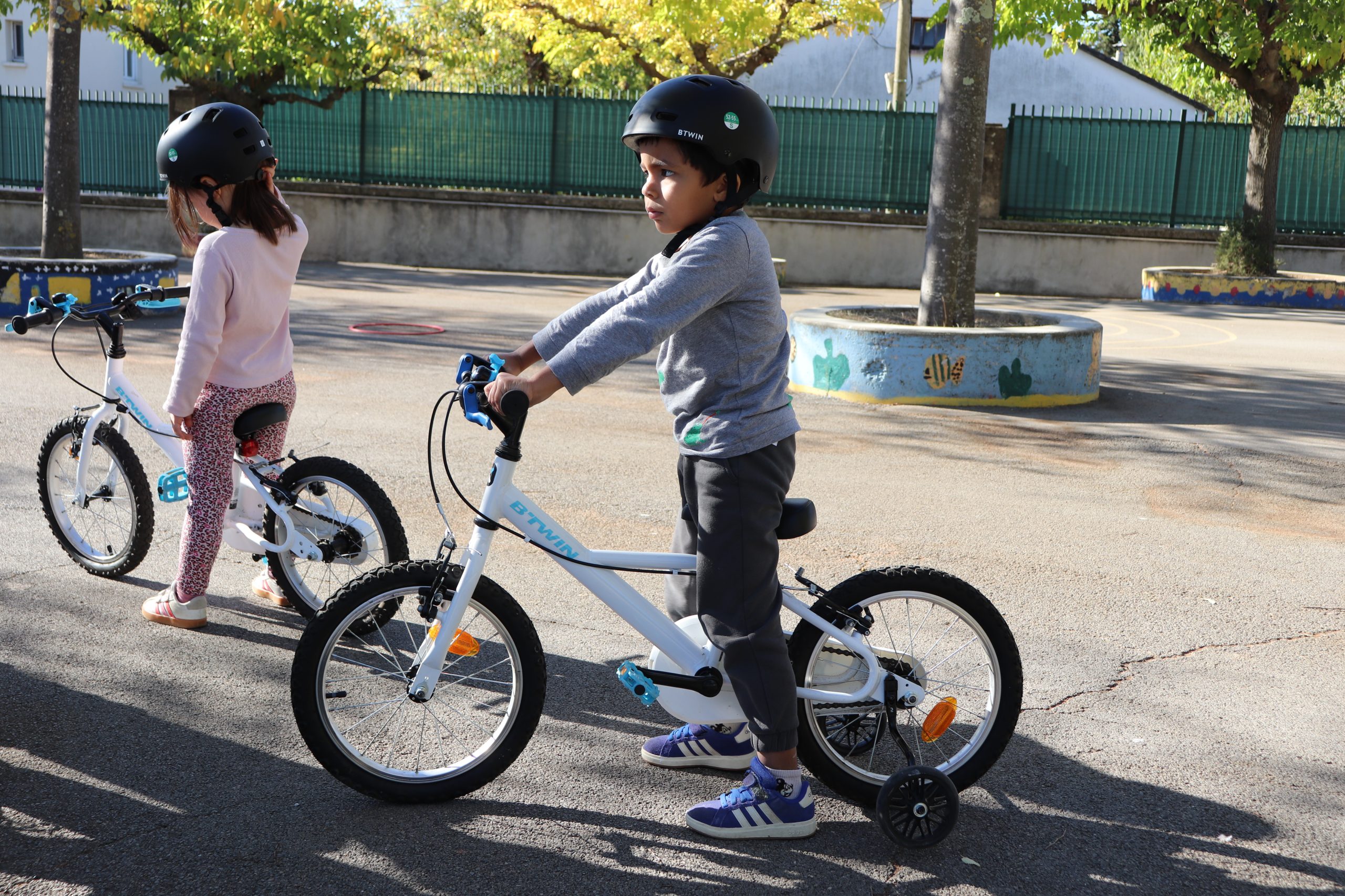 Enfants apprenant à faire du vélo dans la cour.