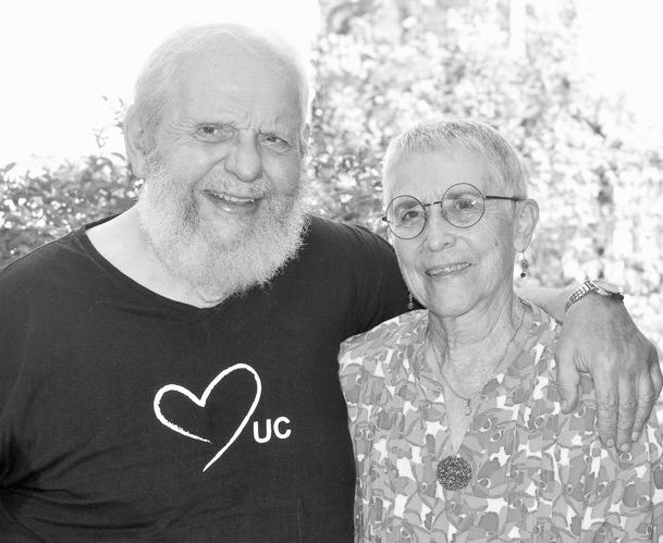 Deux personnes âgées souriantes en extérieur.