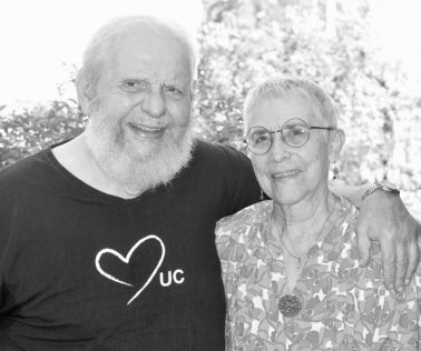 Deux personnes âgées souriantes en extérieur.